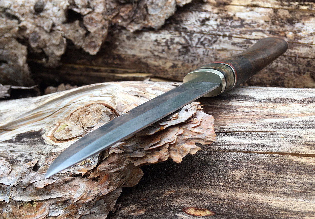 Kleiner Puukko-Verschnitt.
Klinge aus 80CrV2, Griff aus Neusilber, Fiber, Birke, Walnuss.
Verklebt und vernietet.